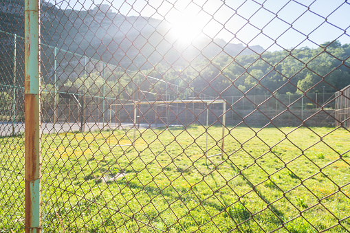 Old rusty tall fence around a soccer court