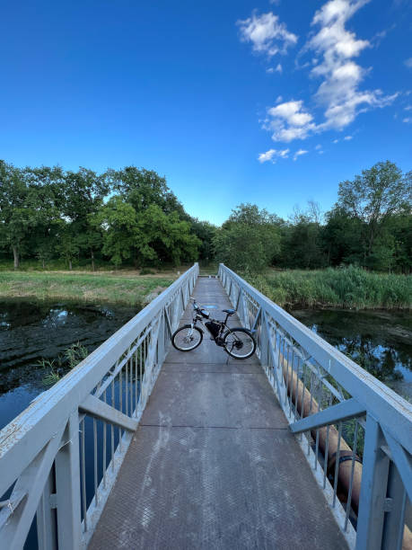 istock Electric bicycle stands among narrow footbridge through river. 1409290741