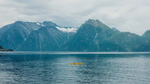 Photo of Aerial view of a woman traveler kayaking on the scenic fjord in Norway
