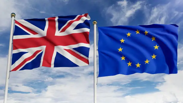 United Kingdom and European Union flags over blue sky. Concept of diplomacy, agreement, international relations, trading, business between England and EU. 3D rendering