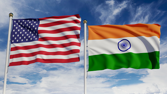 American and Indian flags over blue sky. Concept of diplomacy, agreement, international relations, trading, business between USA and India. 3D rendering