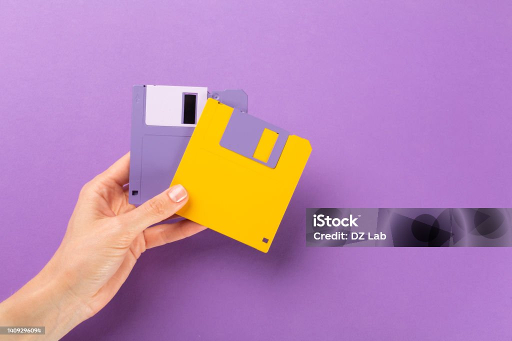 Hand holding floppy disk on color background, technology concept. Hand holding floppy disk on color background, technology concept Floppy Disk Stock Photo