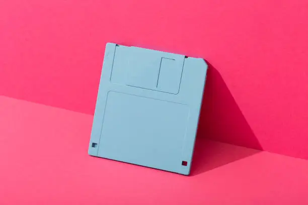 Blue floppy disk on a pink background. High quality photo