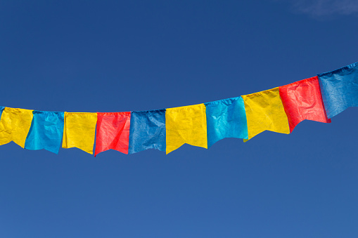 Goiania, Goiás, Brazil – July 17, 2022: A clothesline with fabric pennants against the blue sky for june party - typical brazilian festival. \