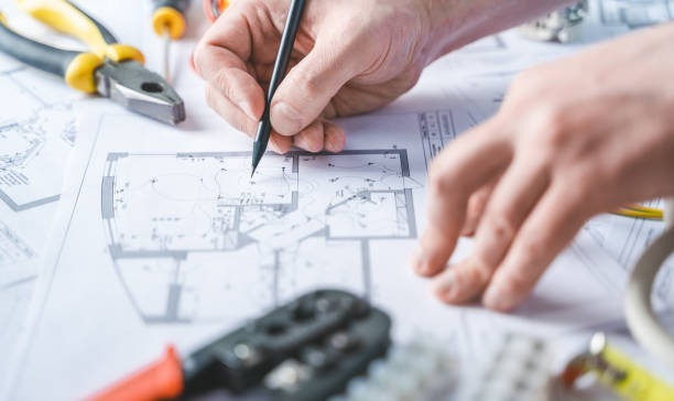 istock Man,repairer making electricity project in house.Repairs planning.Drawings,diagrams,plan for electrification of apartment,building.Devices,accessories,voltmeter,wires,screwdriver,pliers,tape measure 1409296675