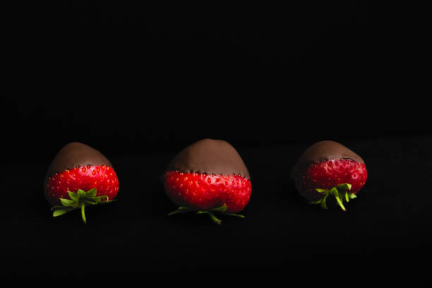 istock Three strawberries in chocolate on the black background 1409296730