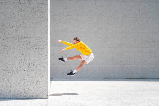 молодой человек прыгает мимо большой бетонной стены на открытом воздухе - skill side view jumping mid air стоковые фото и изображения