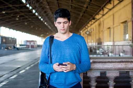 Young man working with cell phone at train station, super attentive to work