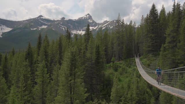 Mountain biker crosses suspension bridge