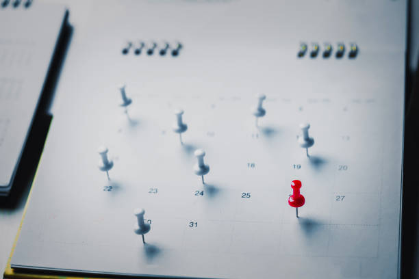 Embroidered red pins on a calendar event Planner calendar,clock to set timetable organize schedule,planning for business meeting or travel planning concept.