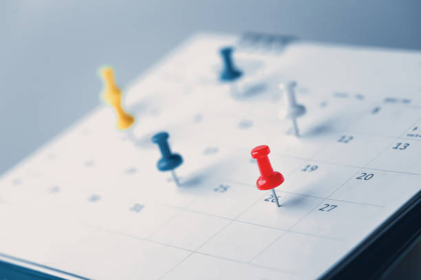 gestickte rote stifte auf einem kalender event planer kalender, uhr zum einstellen des zeitplans organisieren zeitplan, planung für geschäftstreffen oder reiseplanungskonzept. - ereignis stock-fotos und bilder