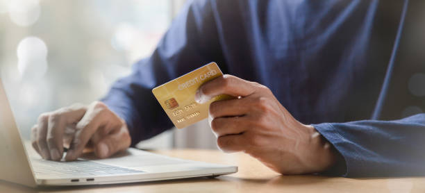 istock Man holding credit card and using smartphone at home online shopping ecommerce internet banking spend money work from home concept. 1409304329
