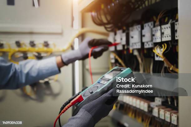 Electricity And Electrical Maintenance Service Engineer Hand Holding Ac Multimeter Checking Electric Current Voltage At Circuit Breaker Terminal And Cable Wiring Main Power Distribution Board Stock Photo - Download Image Now