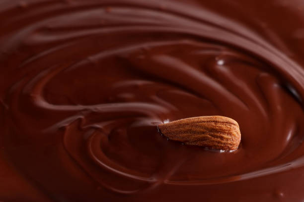 istock Almonds are drowning in melted chocolate. Chocolate background. Selective focus 1409305408