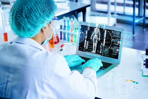 Scientists are using laptop to research cancer or covid treatment in lab. medical human body analysis technology. Scientific research with intelligent AI system innovation Develop an antiviral vaccine