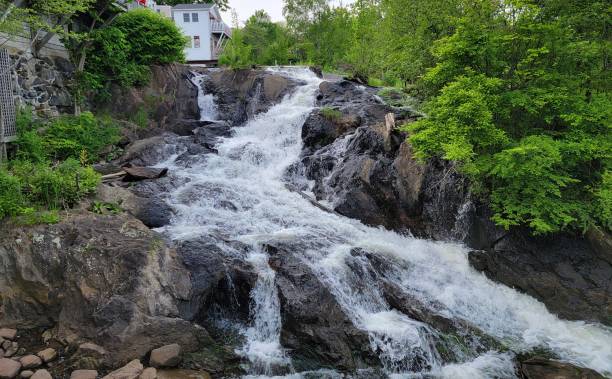 istock rocks and waterfall or cascade with trees and buildings 1409306641