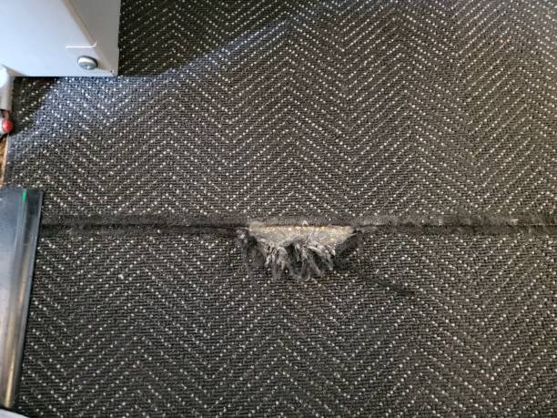 torn black carpet or rug in floor of airplane