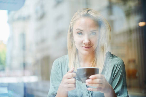 A young woman is drinking coffee in a small business.