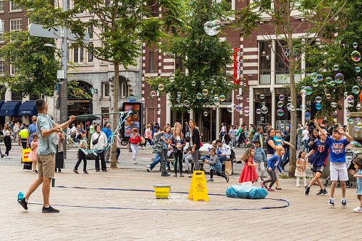 Amsterdam, Netherlands, July 10, 2022; Bubble blower with happy children on a square in the center of Amsterdam.