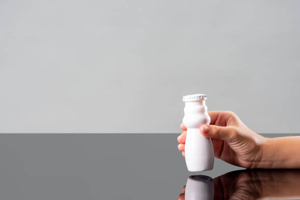 йогурты, содержащие пробиотики, бифидобактерии и витамины. рука кладет белую бутылку как концепцию пробиотической пищи. бифидобактерии и п - acidophile organism стоковые фото и изображения