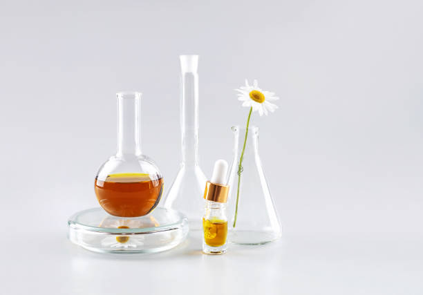 Rose essential oil in a glass bottle set on a wooden board in the grass on a green blurred background