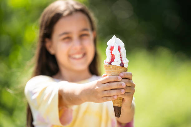 Beautiful little girl eats ice-cream in the summer