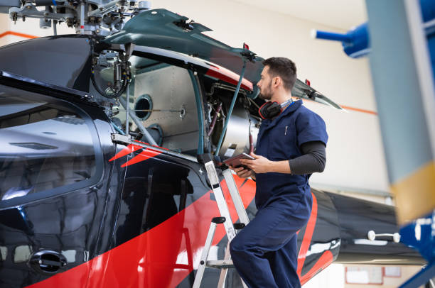 istock Male Aero Engineer With Clipboard Checking On Helicopter In Hangar 1409316276