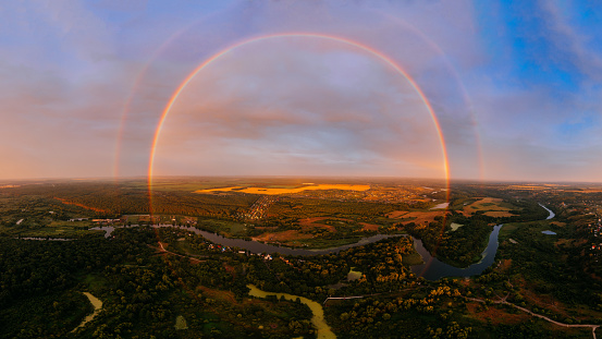 Round rainbow over the river on a summer evening