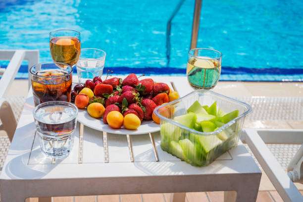 Table relaxing  and fruit plate  strawberries, apricots, cherries by resort pool. Tropical beach luxury lifestyle. Healthy Vegan  Picnic Breakfast in swimming pool,