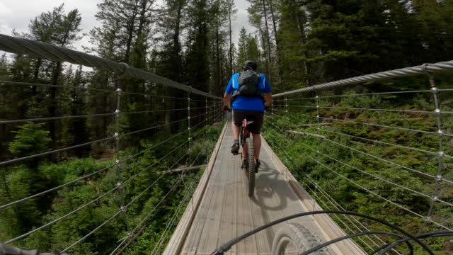 Mountain biker crosses suspension bridge