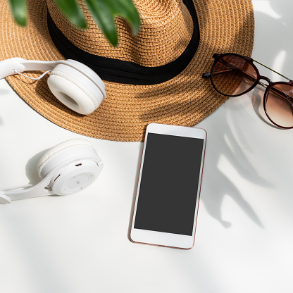 Flat lay of summer item with green tropical leaf and shadow on white desk. Summer, holiday and planning travel concepts. Top view and copy space.