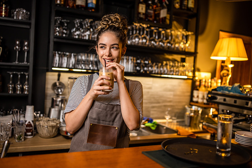 Photo of woman barista drinking a delicious cоffee after she finished her job