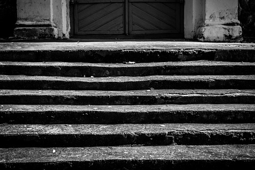 Large stone steps leading to the door of an old church. Black and white.