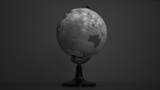 A black and white photo of a desktop globe sitting in the middle of a desk with the Indian Ocean centralised