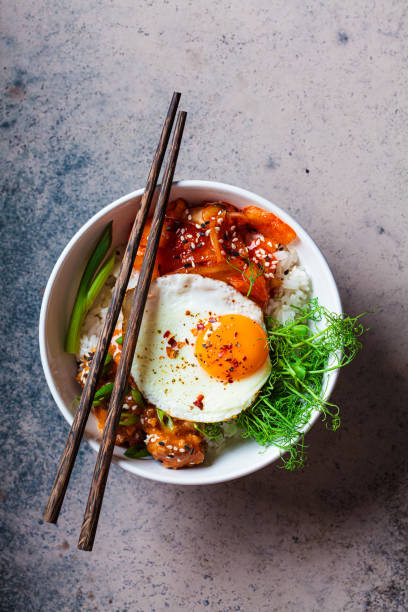 Bibimbap - meat, rice, kimchi, egg and sprouts in white bowl. Traditional Korean food. stock photo