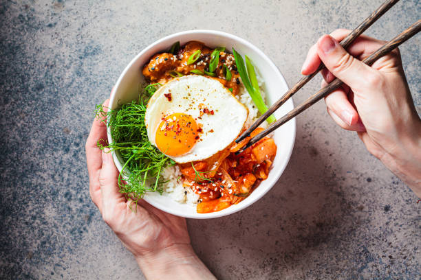 Bibimbap - meat, rice, kimchi, egg and sprouts in white bowl. Traditional Korean food.