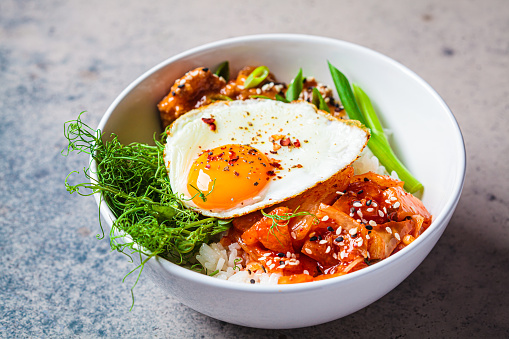 Bibimbap - meat, rice, kimchi, egg and sprouts in a white bowl. Traditional Korean food.