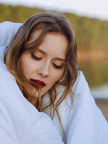 Beautiful young woman wrapped in soft blanket.  Leisure, rest, comfort. Women's routine, everyday life concept. Close up emotional portrait of caucasian young woman