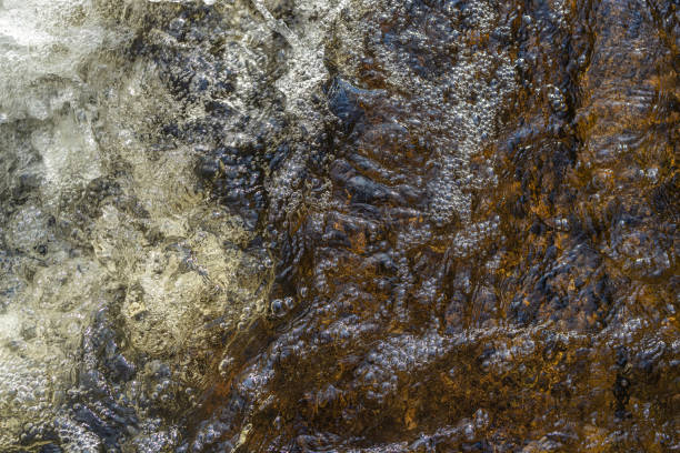 istock Water bubbles and splashes in a heavy stream at the waterfall in closeup. 1409321143