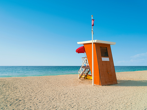 Emplty wooden lifeguard station on sandy beach on ocean shore in summer.