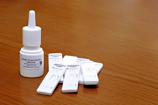 Nasal vaccine vial against the SARS-Cov-2 coronavirus that causes COVID-19, on a wooden table