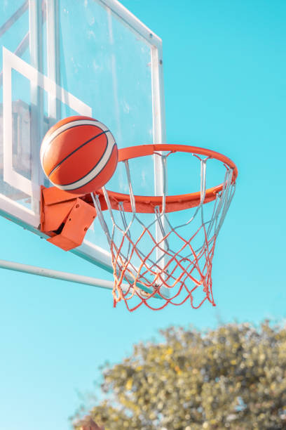 istock An orange basketball ball in hoop on a blue sky background. Side view 1409323643