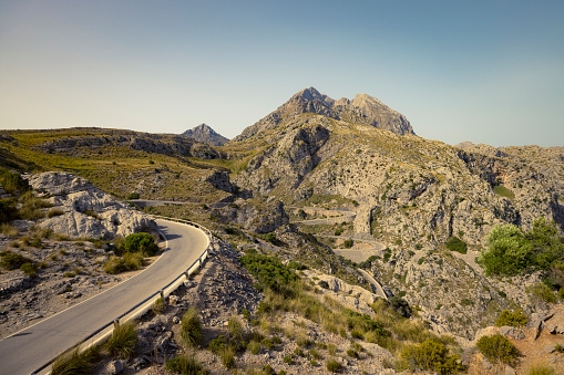 Aerial drone panorama of Transalpina road winding along sharp mountain peaks and near a steep abyss. The alpine pastures of Parang Mountains are crowded with tourists. Carpathia, Romania