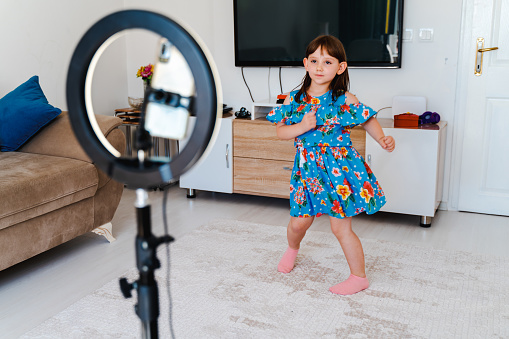 little beauty blogger filming videos at home and dancing to camera set on ring light, young blogger concept, copy space