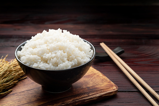 Cooked Thai rice in black bowl on wooden background