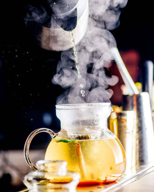 Organic herbal tea in a transparent teapot with steam is poured with hot water. Healthy tea preparation. 
Tea ceremony for relaxation and relaxation. Slow life concept stock photo