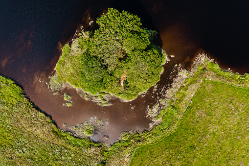 Bird's-eye view of a small island in a river flowing through a rural location in Scotland