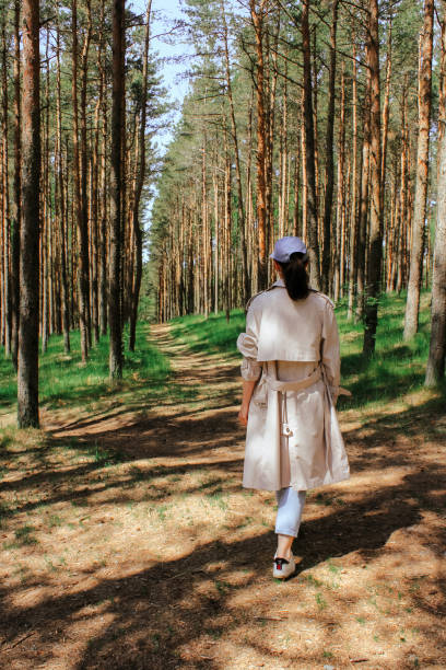 istock a woman walks along the road through a young pine forest 1409336294