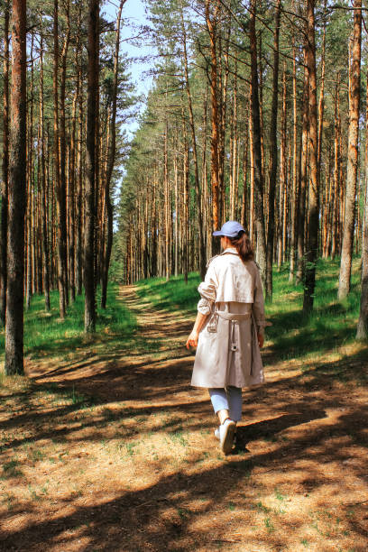 istock a woman walks along the road through a young pine forest 1409336323
