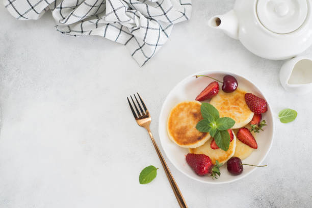 istock Cottage cheesecakes with berries and mint in a white plate on a white background. Top view. 1409336533